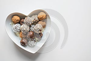 Homemade natural energy bites, vegan chocolate truffle with cacao on white. Healthy food for children, sweets substitute