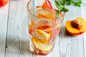 Homemade nectarine iced tea or lemonade with fresh mint and ice cubes in glass