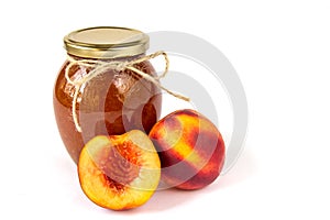 Homemade nectarine jam in a glass jar and fresh peaches on the wallpaper