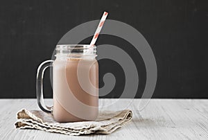 Homemade New England Chocolate Milkshake in a Glass Jar Mug on a white wooden background, side view. Copy space