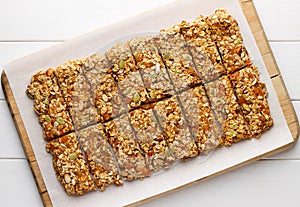 Homemade no bake granola bars with oat flakes, honey, dried apricots and seeds on white baking paper. photo