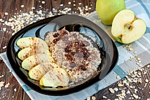 Homemade oatmeal with apple, cinnamon, hazelnuts, honey and peanuts on dark wooden background