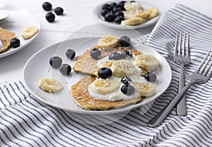 Homemade oatmeal pancakes with yogurt, fresh blueberry and banana at white wooden background