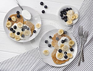 Homemade oatmeal pancakes with yogurt, fresh blueberry and banana at white wooden background