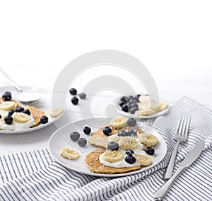 Homemade oatmeal pancakes with yogurt, fresh blueberry and banana at white wooden background