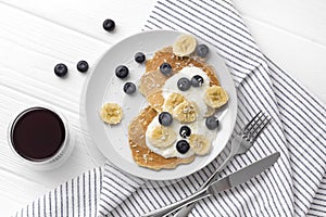 Homemade oatmeal pancakes with yogurt, fresh blueberry and banana at white wooden background