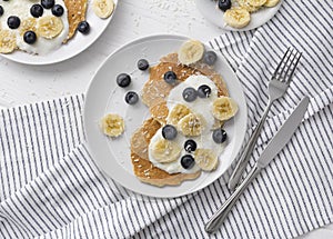 Homemade oatmeal pancakes with yogurt, fresh blueberry and banana at white wooden background