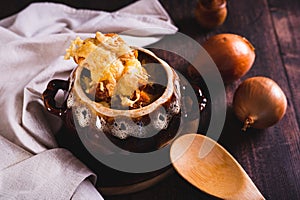 Homemade onion soup with cheese croutons in a pot on the table