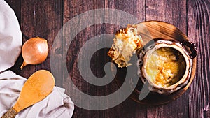 Homemade onion soup with cheese croutons in a pot on the table top view web banner