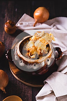 Homemade onion soup with cheese croutons in a pot on the table vertical view