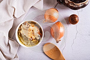 Homemade onion soup with croutons and cheese in a bowl on the table top view