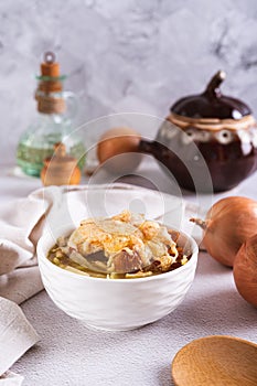 Homemade onion soup with croutons and cheese in a bowl on the table vertical view