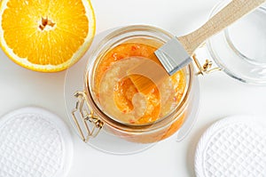 Homemade orange fruit facial mask exfoliating sugar scrub in the glass jar. Citrus DIY beauty treatment and spa recipe. Top view