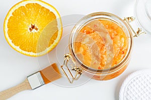 Homemade orange fruit facial mask exfoliating sugar scrub in the glass jar. Citrus DIY beauty treatment and spa recipe. Top view