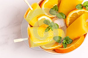 Homemade orange popsicle with ripe orange and fresh mint