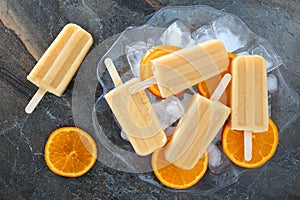 Homemade orange yogurt popsicles in an ice filled bowl