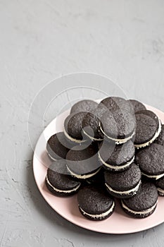 Homemade Oreos on a pink plate on a gray background, side view. Space for text