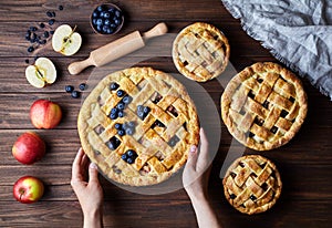 Homemade organic apple pies bakery products hold female hands on dark wooden kitchen table with raising, bluberry