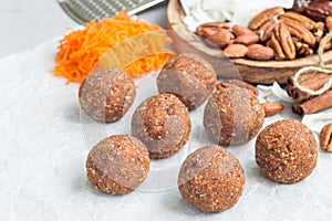 Homemade paleo energy balls with carrot, nuts, dates and coconut flakes, on parchment, horizontal, copy space