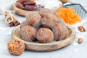 Homemade paleo energy balls with carrot, nuts, dates and coconut flakes, on wooden plate, horizontal