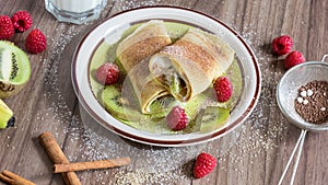 Homemade pancake with vanilla curd, raspberries, kiwi and banana pieces sprinkled with cocoa