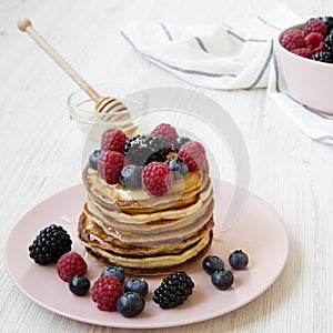 Homemade pancakes with berries and honey, side view. Closeup
