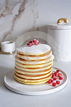 Homemade pancakes on white plate wih berries