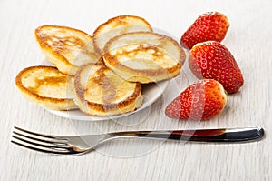 Pancakes in saucer, several strawberries, fork on table