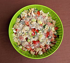 Homemade Panzanella in a green bowl. It is summer chopped salad of soaked stale bread, onions, basil and tomatoes.