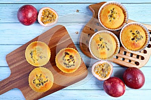 Homemade Passion Fruit Muffins on Breadboard with Fresh Ripe Passion Fruits on Pale Blue Wooden Table