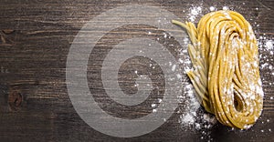 Homemade pasta with flour on wooden rustic background top view close up border, place for text