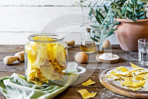 Homemade pasta Maltagliat in jar and wooden cutting boardi with ingredients in rustic style