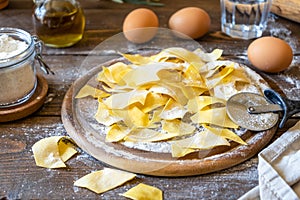 Homemade pasta Maltagliati on cutting board with ingredients on wooden background. Close up