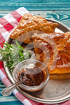 Homemade pastries on a metallic dish with sauce and rosemary