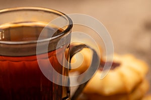 Homemade pastry cookies with jam and a faceted glass of tea in a vintage Cup holder on a background of homespun fabric with a