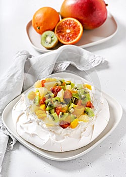Homemade Pavlova cake dessert with meringue and fresh fruit slices of kiwi, mango, pineapple and blood orange.