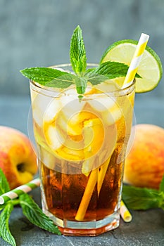 Homemade peach ice tea with ice, lime and mint in the glass