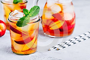 Homemade peach iced tea or lemonade with fresh mint and ice cubes in glass jar