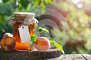 Homemade Peach Jam in Glass Jar Illuminated by Sunlight on Rustic Wooden Table Outdoors