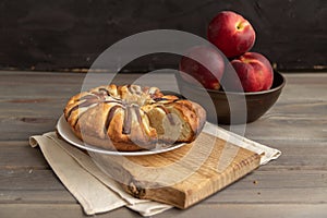 homemade peach pie on a wooden board on a black background