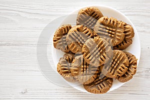 Homemade Peanut Butter Cookies on a plate on a white wooden background, top view. Flat lay, overhead, from above. Space for text