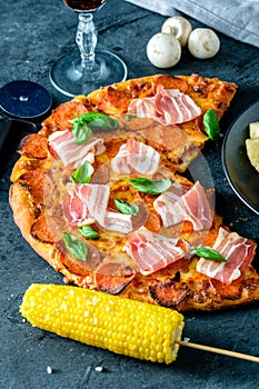 Homemade Pepperoni Pizza with fresh bacon over black background