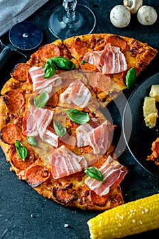 Homemade Pepperoni Pizza with fresh bacon over black background