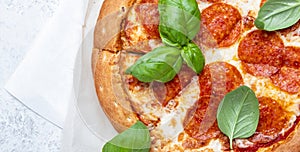 Homemade pepperoni pizza with spicy sausage, mozzarella cheese, tomato sauce and green basil leaves, white background, top view