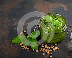 Homemade pesto sauce fresh Basil and nuts on dark background