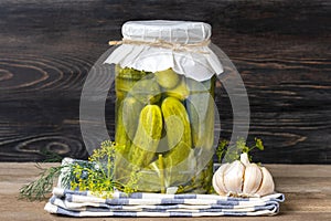 Homemade pickled cucumbers, garlic in jars on wooden shelf Homemade canned and fermented foods concept Seasonal product