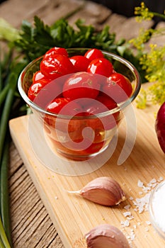 Homemade pickled tomatoes. Bowl of canned tomatoes. Marinated vegetables in a glass jars on background