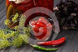 Homemade pickled tomatoes. Bowl of canned tomatoes. Marinated vegetables in a glass jars on background