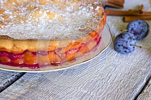 Homemade pie with plums on the white rustic table.