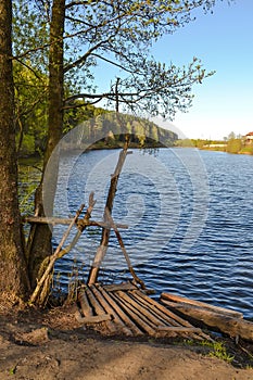 Homemade pier for fishermen from the thick branches on the lake.